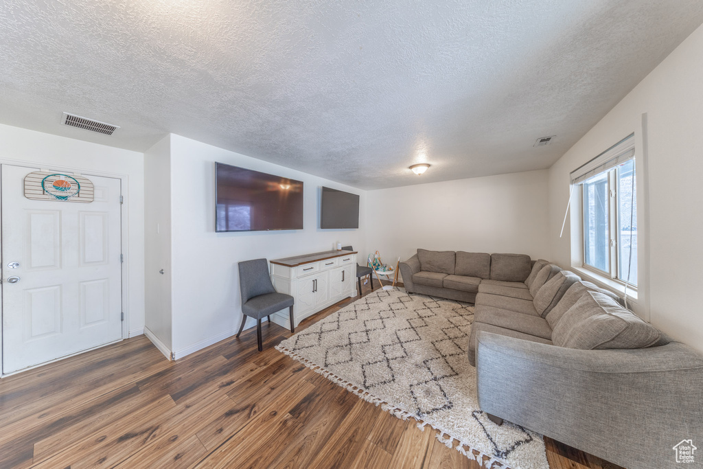 Living area featuring a textured ceiling, wood finished floors, and baseboards