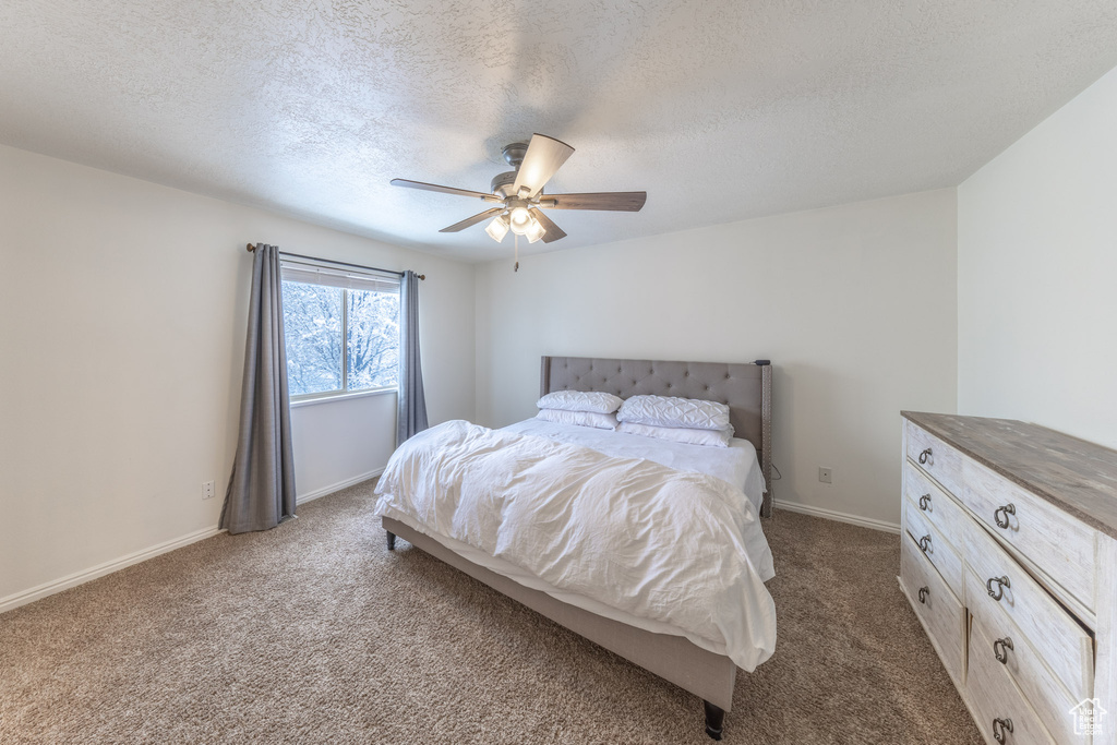 Bedroom featuring dark colored carpet, a textured ceiling, a ceiling fan, and baseboards