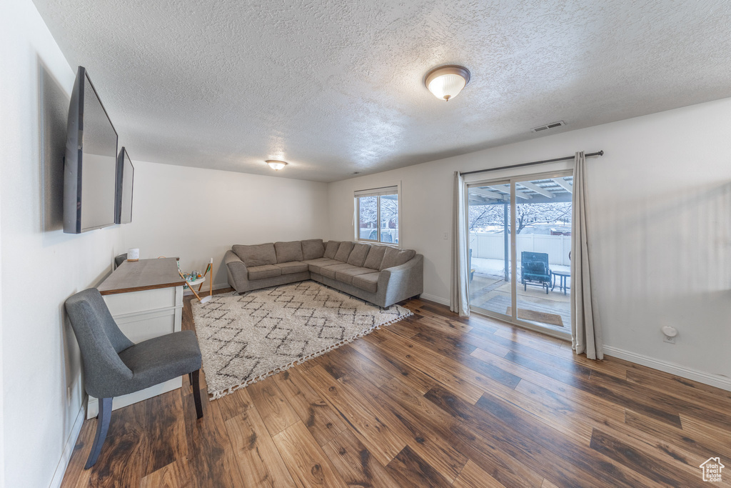 Living area with a textured ceiling, wood finished floors, and baseboards