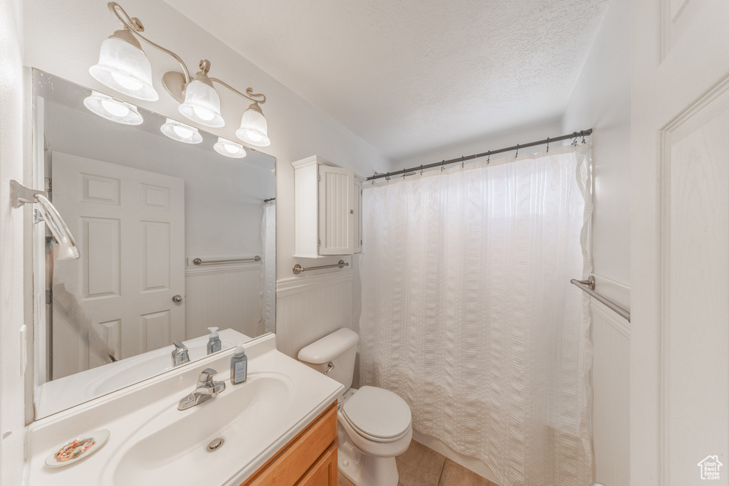 Bathroom with toilet, vanity, tile patterned flooring, and a shower with shower curtain