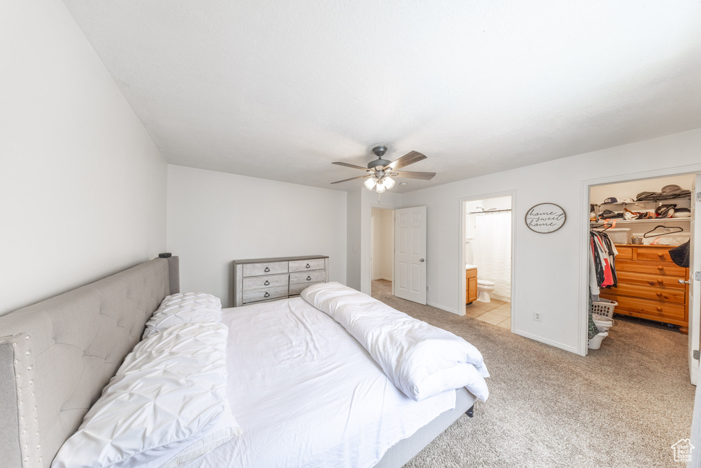 Bedroom featuring a walk in closet, light carpet, a closet, ceiling fan, and ensuite bathroom