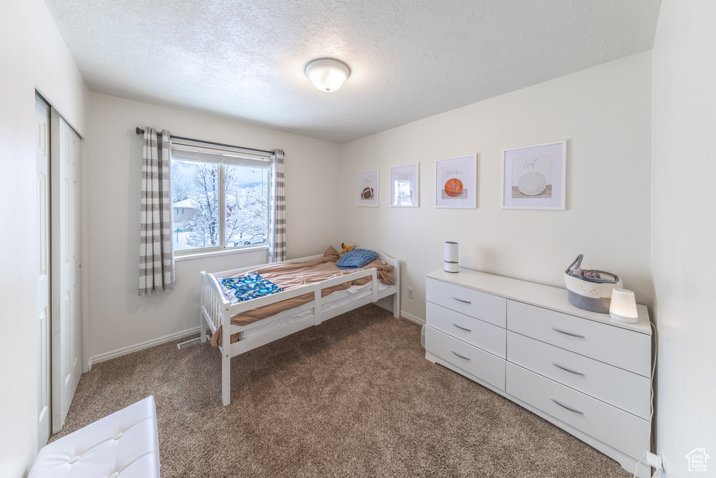 Bedroom with carpet, a textured ceiling, and baseboards