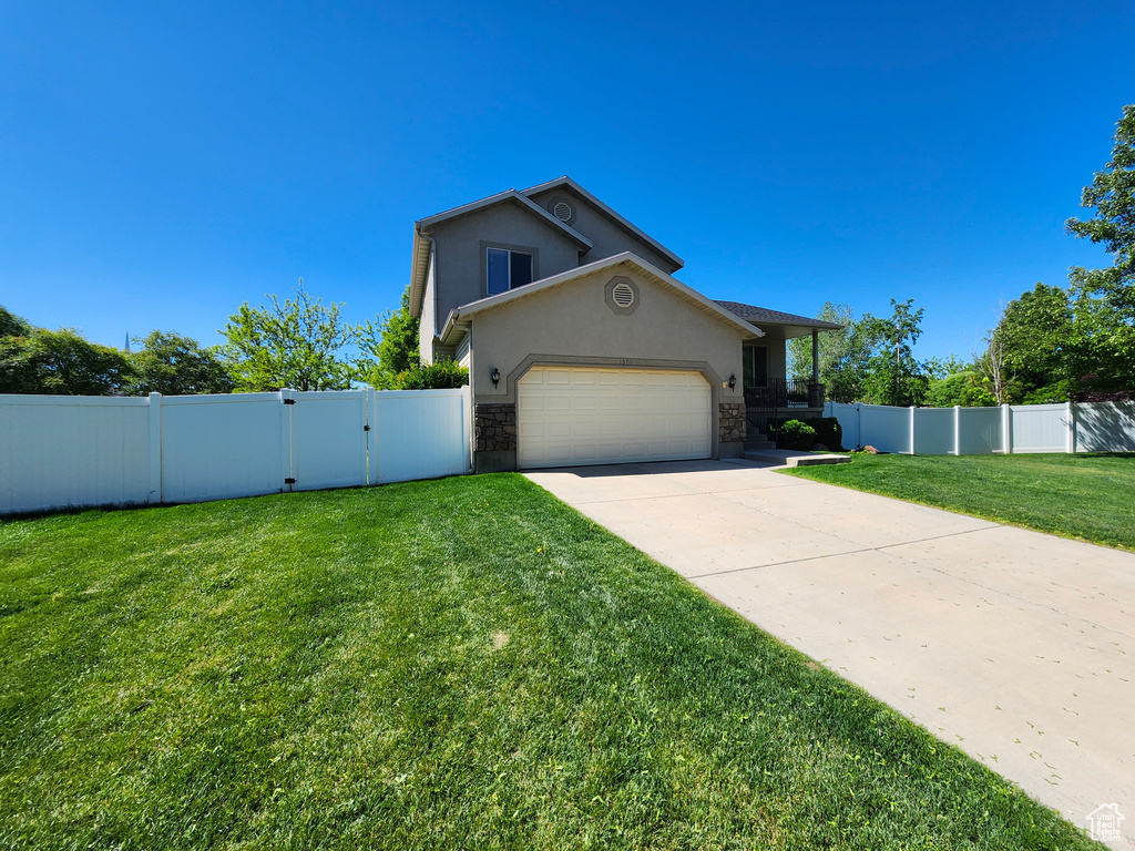View of front of home featuring stucco siding, driveway, a garage, stone siding, and a gate
