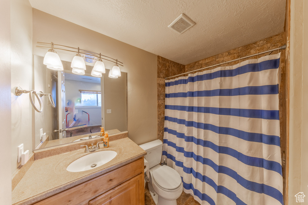 Full bath featuring toilet, a textured ceiling, vanity, and curtained shower