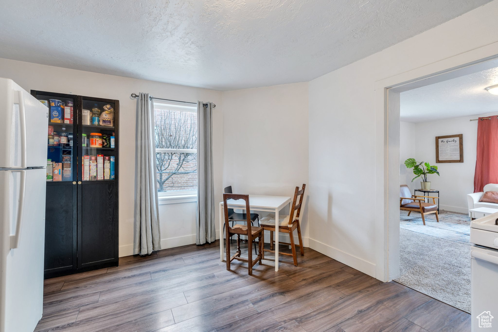 Dining space with wood finished floors, baseboards, and a textured ceiling