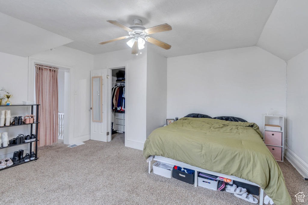 Carpeted bedroom featuring baseboards, lofted ceiling, ceiling fan, a spacious closet, and a closet