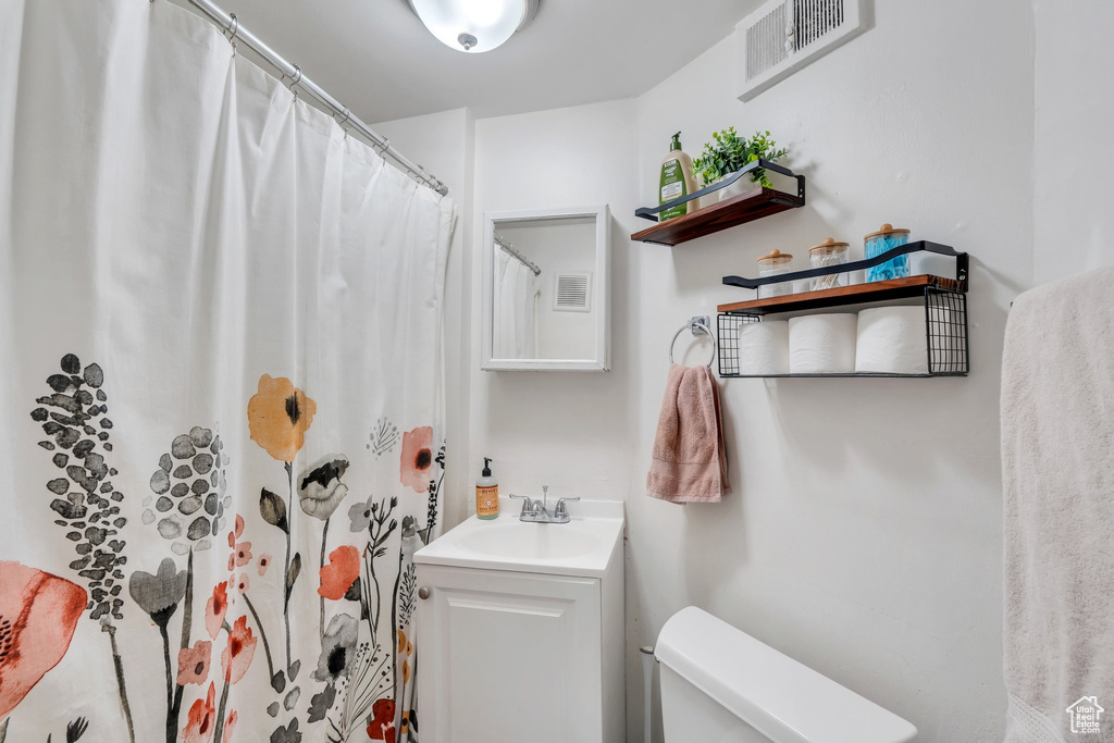 Full bath with toilet, vanity, and a shower with shower curtain