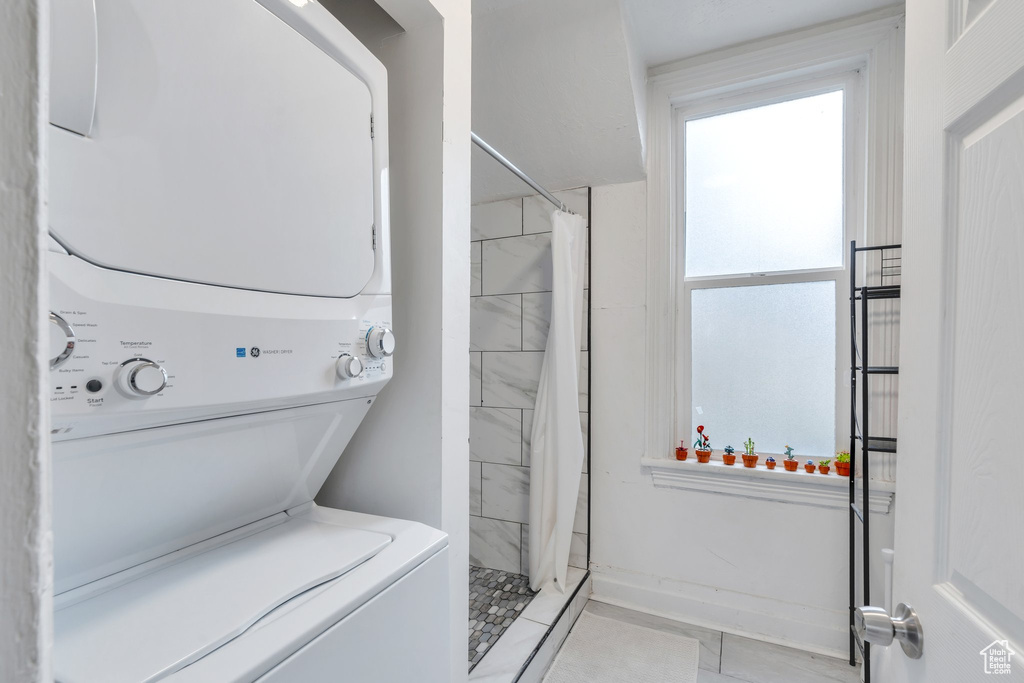 Full bath featuring estacked washer and dryer, a shower stall, and tile patterned flooring