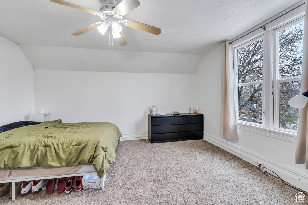 Bedroom with vaulted ceiling, carpet, multiple windows, a ceiling fan, and baseboards