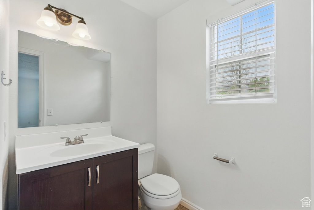 Half bathroom with vanity, toilet, and baseboards