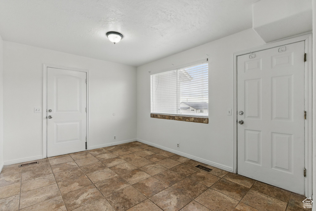 Foyer with baseboards, a textured ceiling, and stone finish flooring