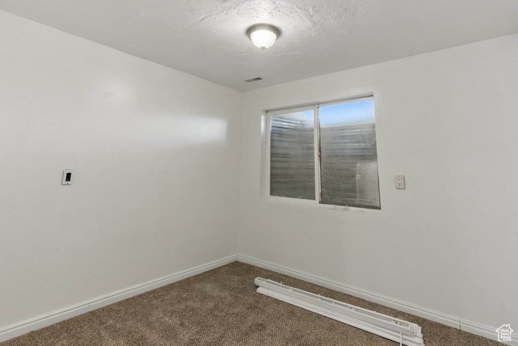 Unfurnished room featuring dark carpet, baseboards, and baseboard heating
