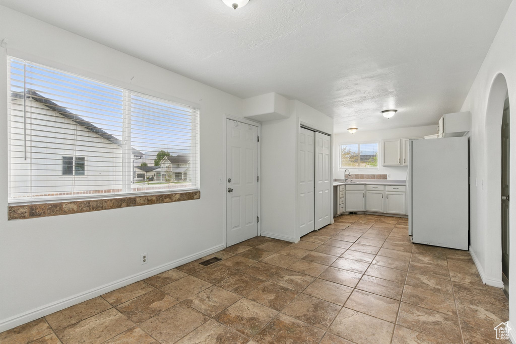 Kitchen with freestanding refrigerator, baseboards, a sink, and light countertops
