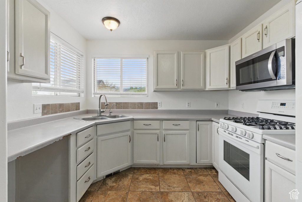 Kitchen featuring stainless steel microwave, gas range gas stove, a sink, and light countertops