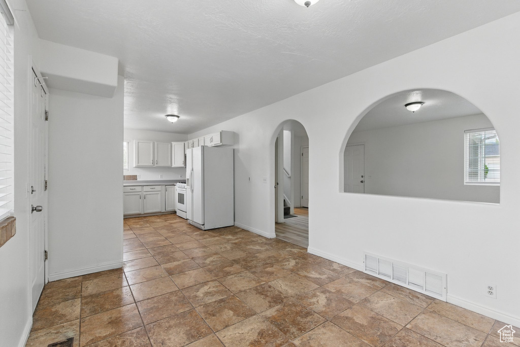 Kitchen featuring white appliances, baseboards, arched walkways, and stone finish flooring