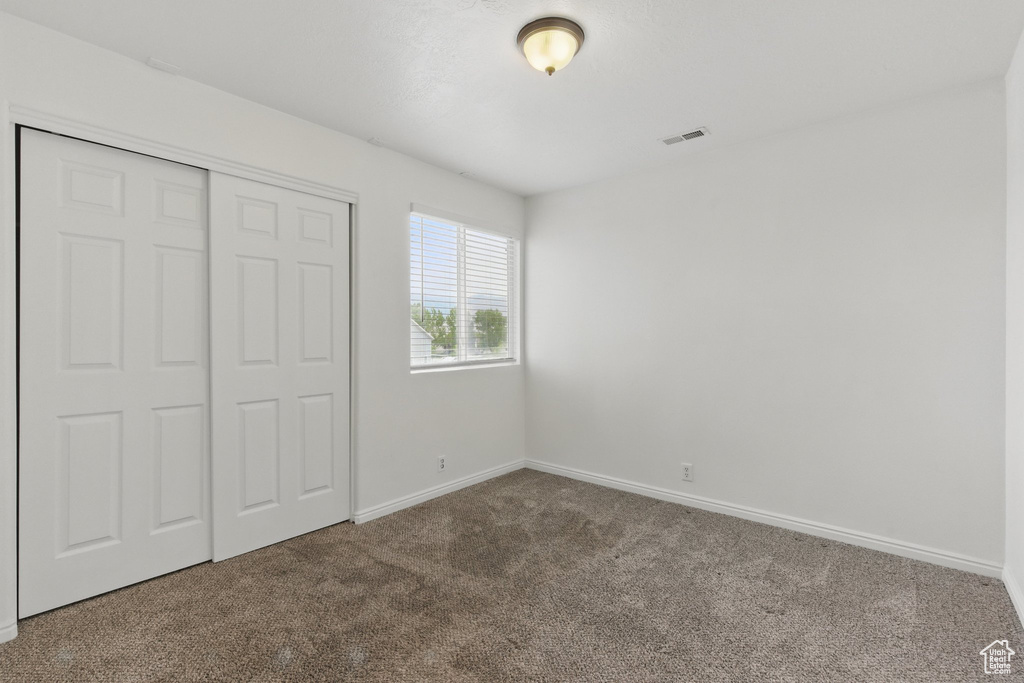 Unfurnished bedroom featuring carpet, baseboards, and a closet