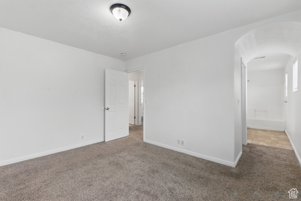Carpeted spare room with arched walkways and baseboards