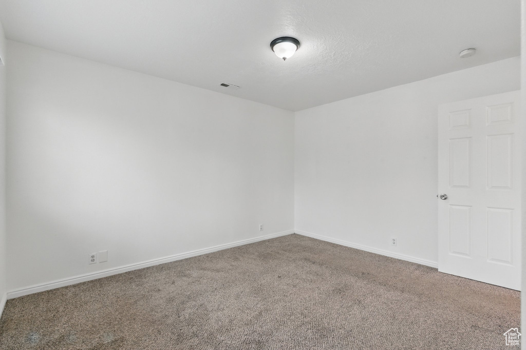 Empty room featuring carpet floors, baseboards, and a smoke detector