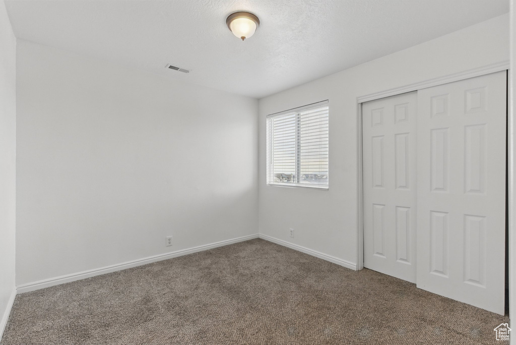Unfurnished bedroom with carpet floors, baseboards, and a closet
