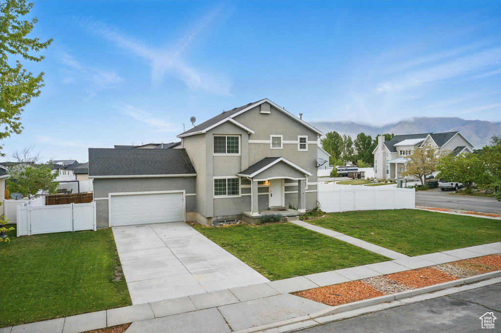 Traditional home with a mountain view, concrete driveway, stucco siding, a garage, and roof with shingles