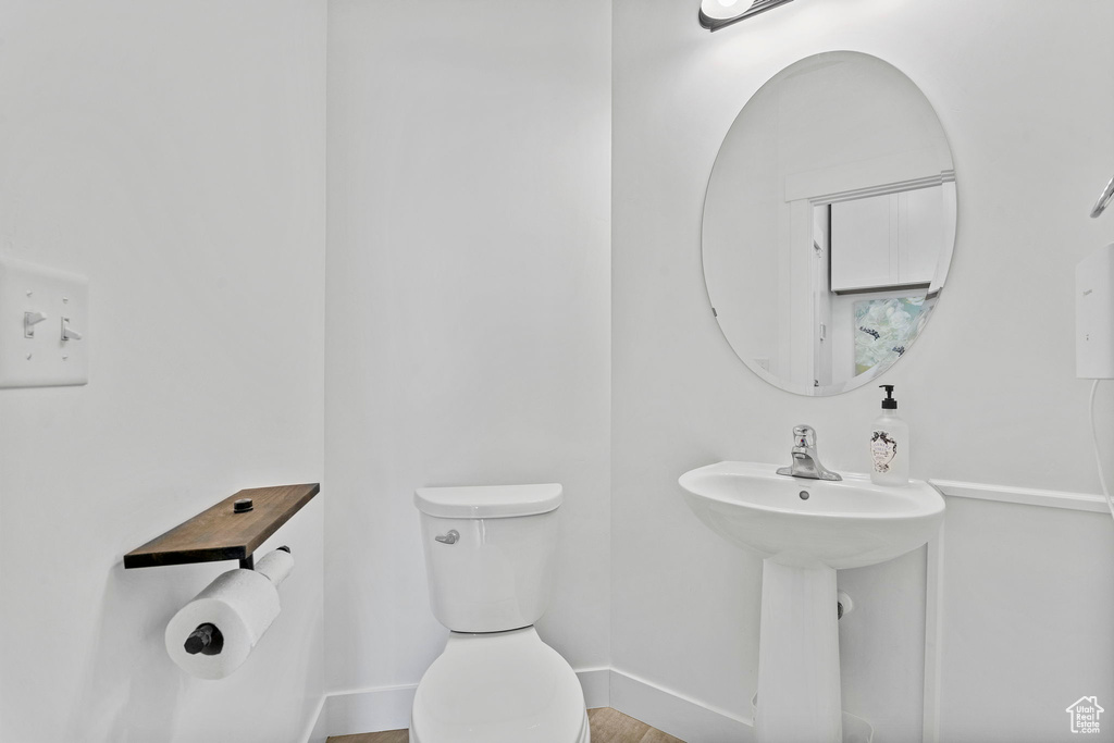 Half bath featuring toilet, baseboards, and a sink