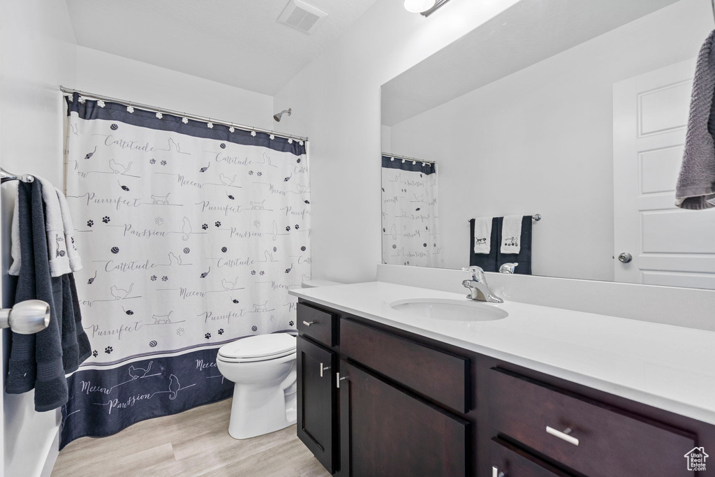 Full bath with wood finished floors, toilet, vanity, and a shower with curtain