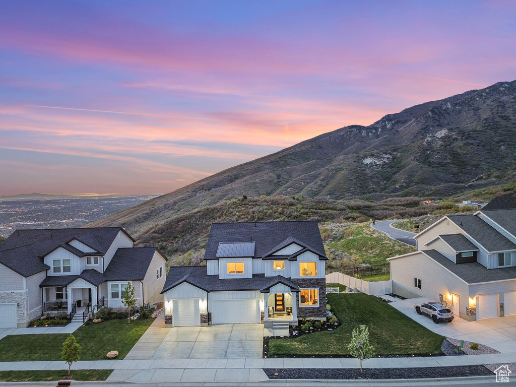 View of front facade with driveway, a mountain view, stone siding, board and batten siding, and an attached garage