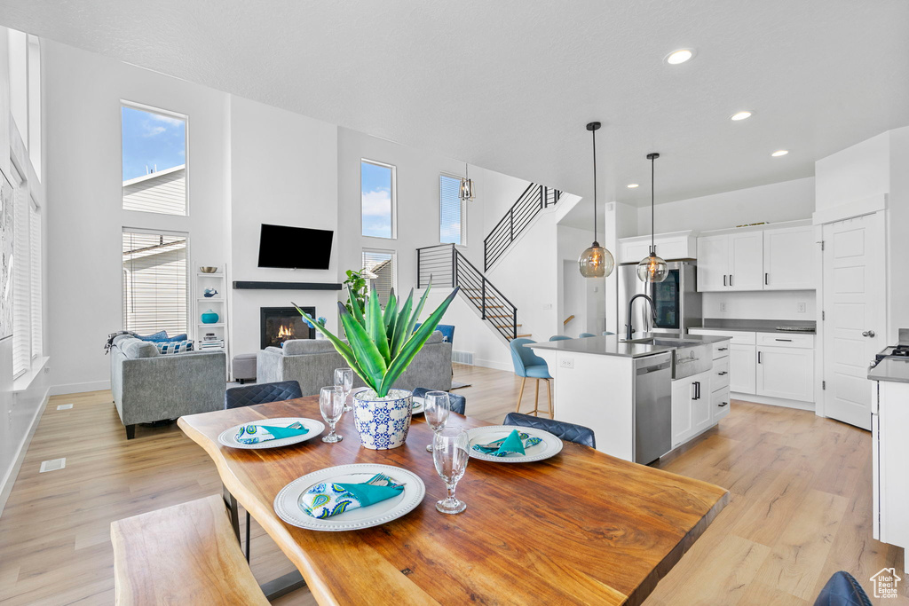 Dining space with recessed lighting, baseboards, light wood-style floors, a glass covered fireplace, and stairway