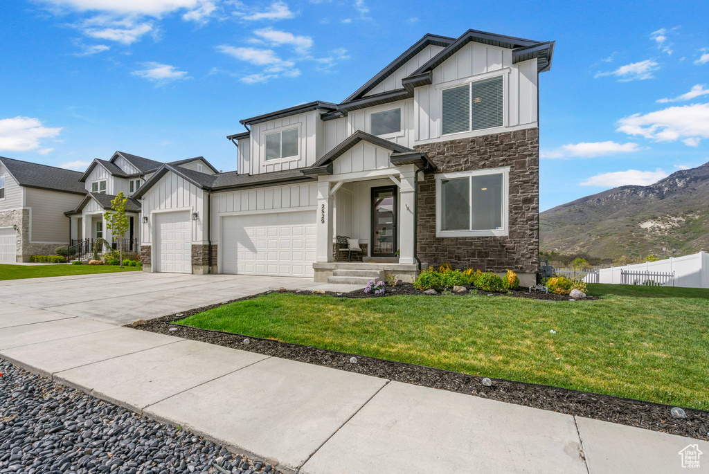 View of front facade featuring board and batten siding, stone siding, concrete driveway, and a mountain view