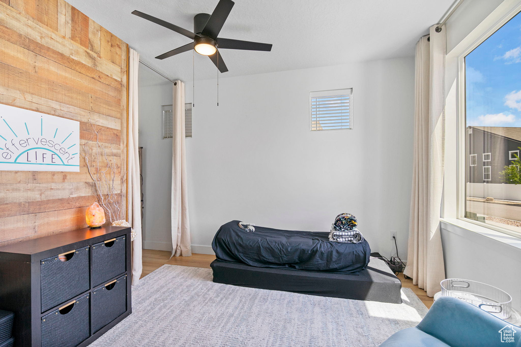 Bedroom featuring wood finished floors, wood walls, and a ceiling fan