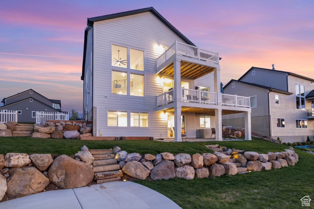 Rear view of property featuring a balcony, a patio, and a lawn