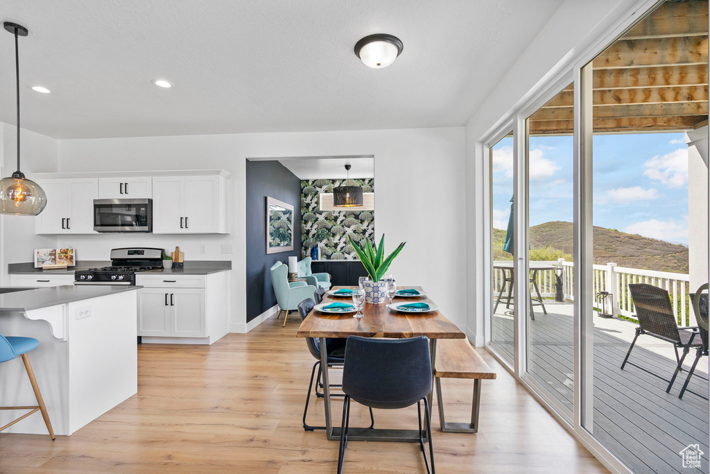 Kitchen featuring appliances with stainless steel finishes, white cabinets, light wood-type flooring, pendant lighting, and recessed lighting