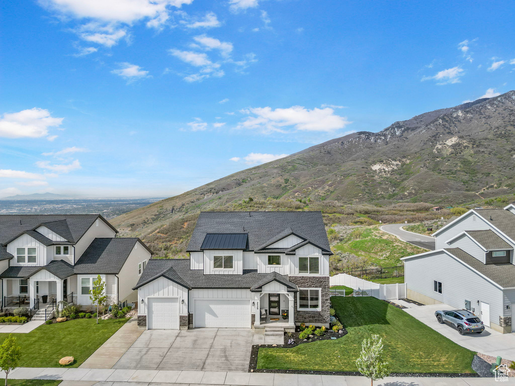 View of front facade featuring board and batten siding, stone siding, concrete driveway, a mountain view, and a residential view