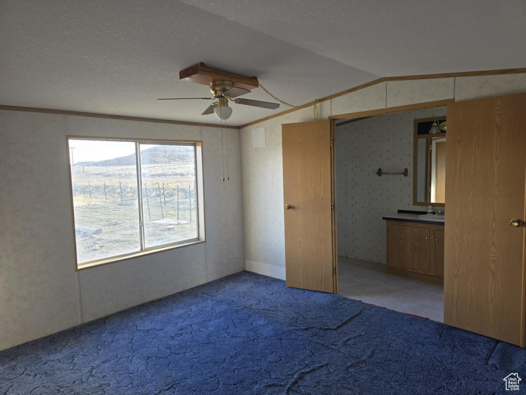 Unfurnished bedroom with light colored carpet, vaulted ceiling, a ceiling fan, connected bathroom, and crown molding