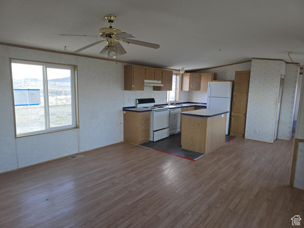 Kitchen featuring white appliances, under cabinet range hood, wood finished floors, a ceiling fan, and a center island