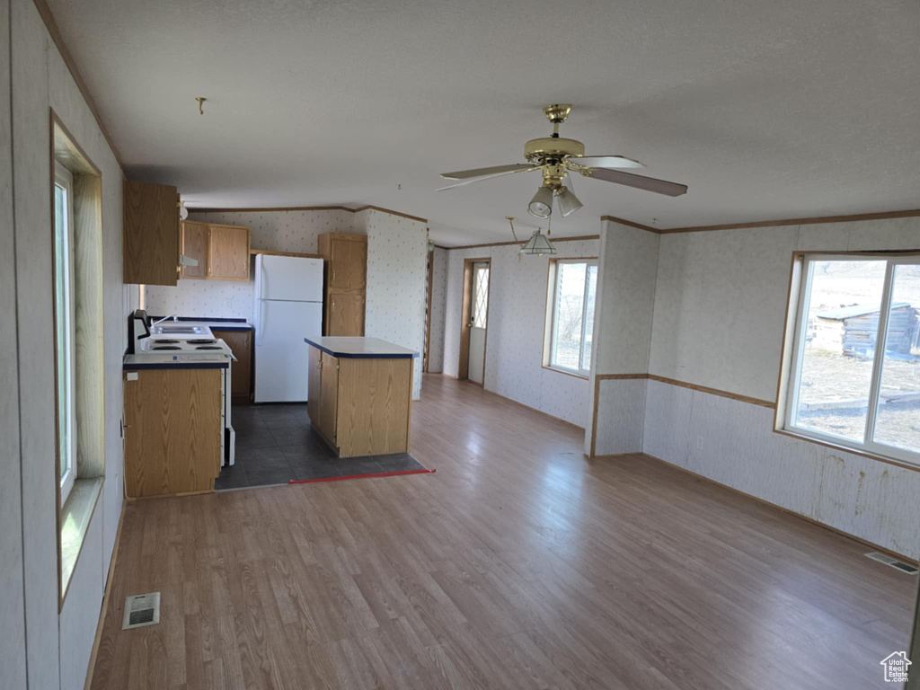 Kitchen featuring freestanding refrigerator, wallpapered walls, a kitchen island, dark wood finished floors, and open floor plan