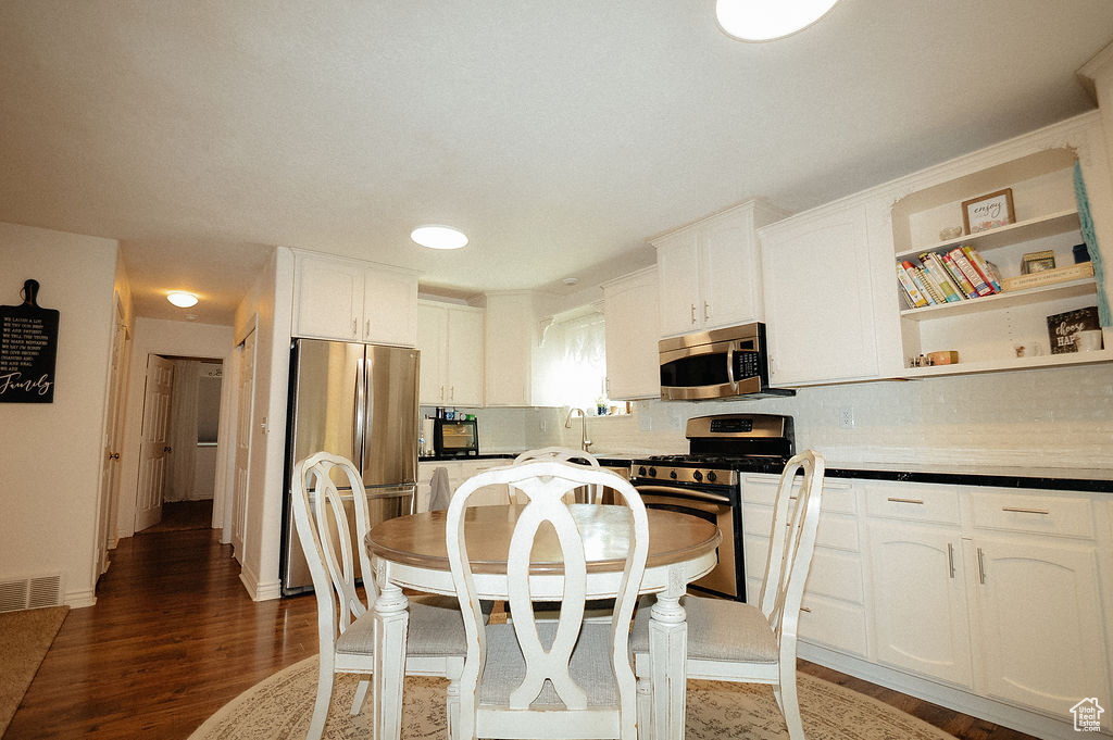 Kitchen featuring stainless steel appliances, backsplash, white cabinets, and wood finished floors