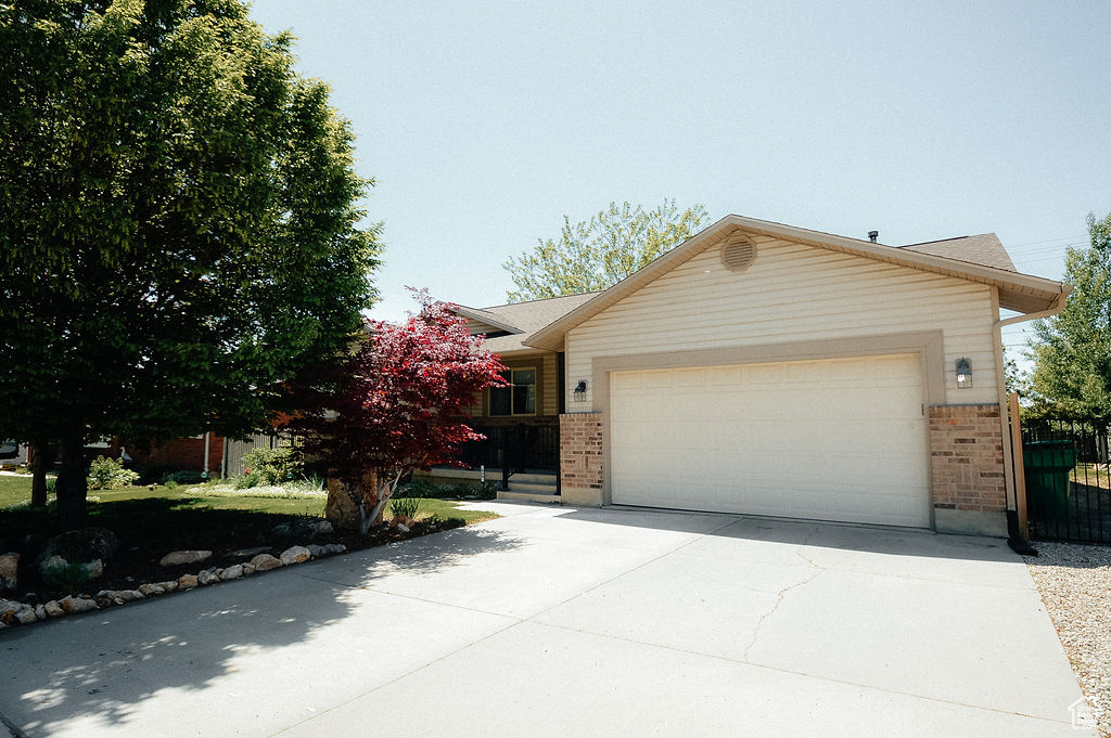 Single story home with brick siding, an attached garage, and driveway