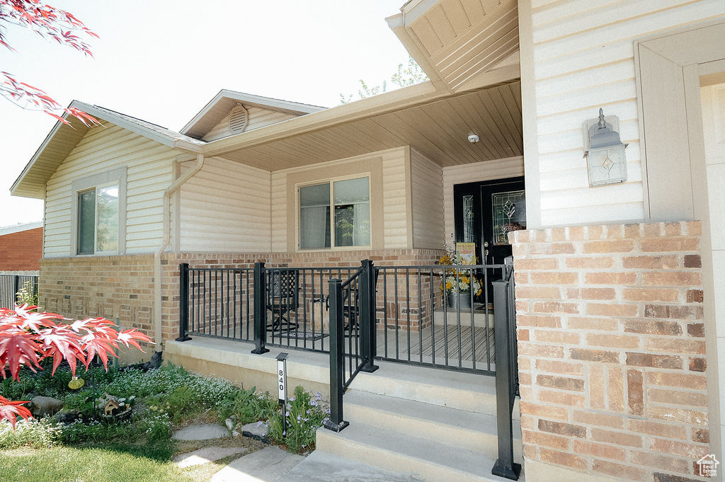 Entrance to property featuring brick siding and covered porch