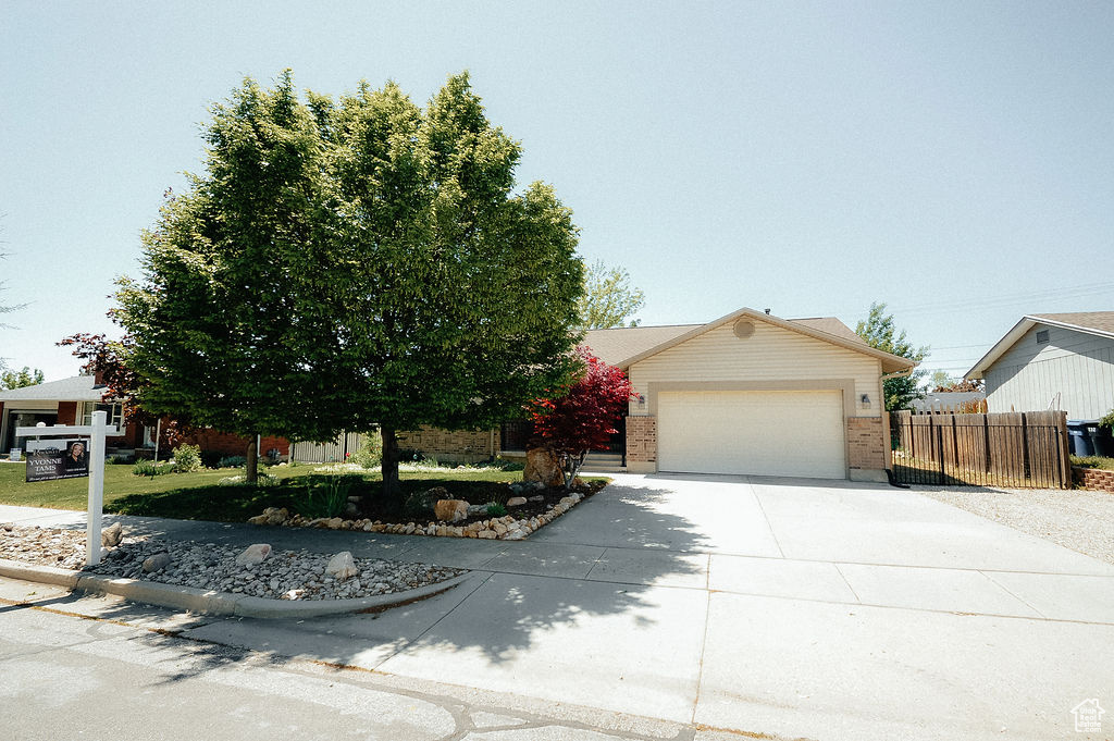 View of front of house featuring concrete driveway, fence, a garage, and brick siding