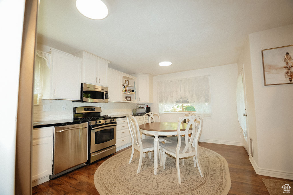 Kitchen with appliances with stainless steel finishes, white cabinets, tasteful backsplash, dark wood finished floors, and open shelves