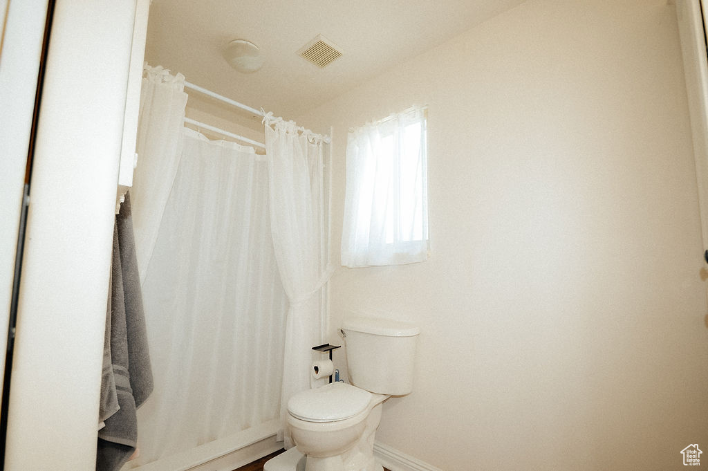 Full bath with toilet, baseboards, and curtained shower