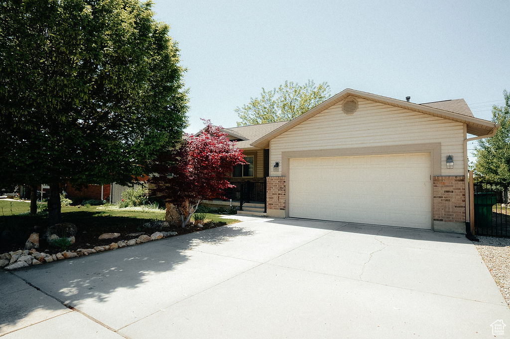 Ranch-style house featuring brick siding, a garage, driveway, and fence