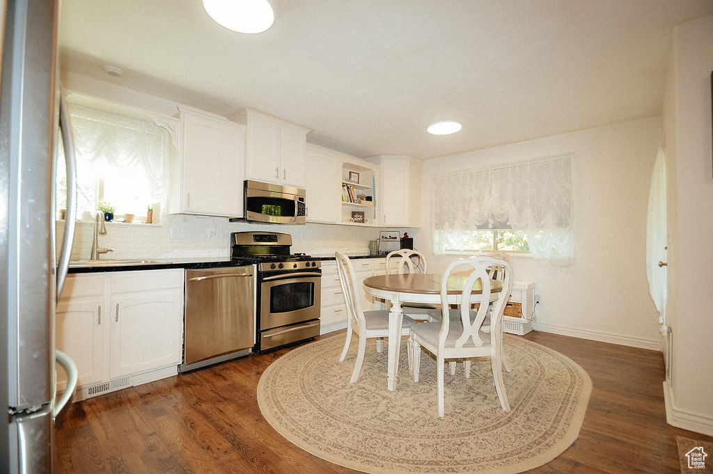 Kitchen with appliances with stainless steel finishes, open shelves, backsplash, white cabinetry, and recessed lighting