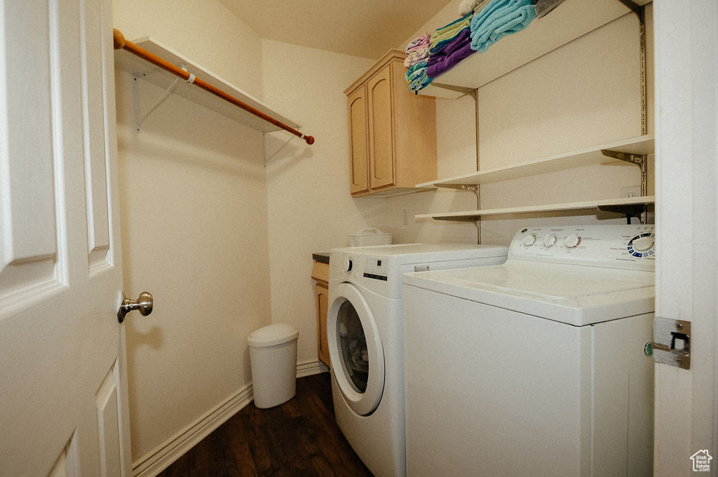 Washroom featuring washer and clothes dryer, dark wood-type flooring, cabinet space, and baseboards