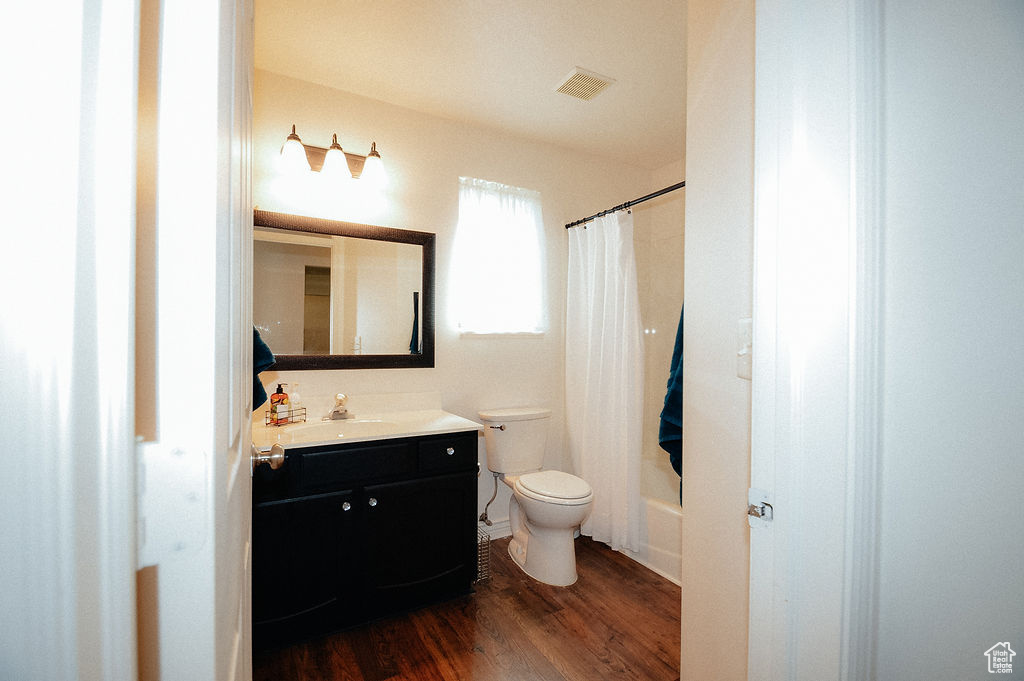 Bathroom featuring vanity, toilet, wood finished floors, and shower / tub combo
