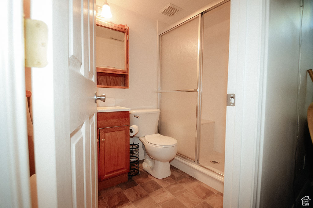 Bathroom featuring a stall shower, toilet, and vanity