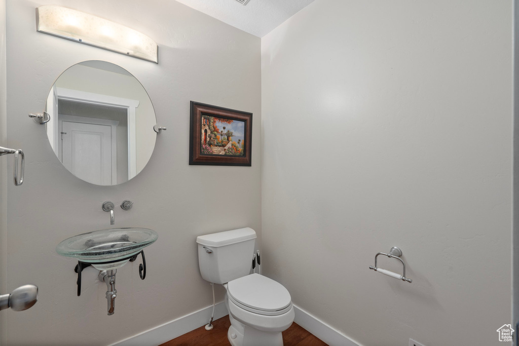 Bathroom featuring toilet, wood finished floors, and baseboards