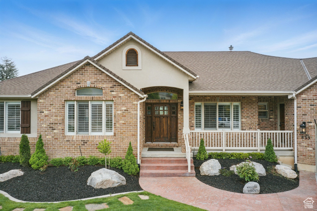 Single story home with brick siding, a porch, and stucco siding