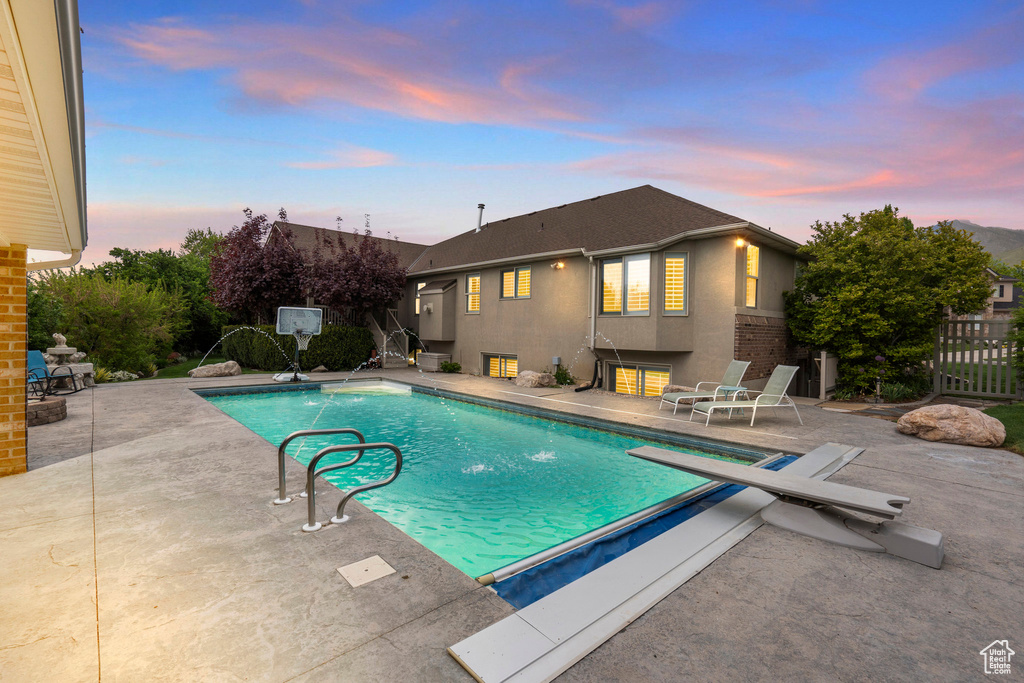 Pool at dusk featuring a patio and fence
